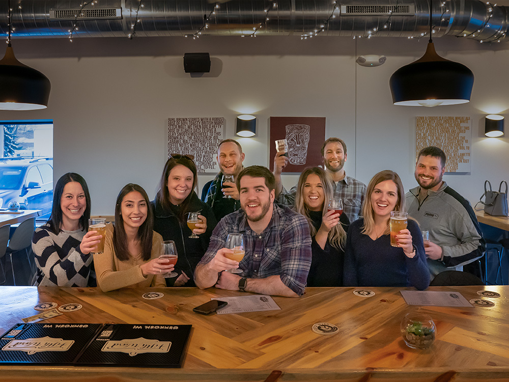 Group of people toasting with beer in the taproom at the Fifth Ward Brewery in Oshkosh.